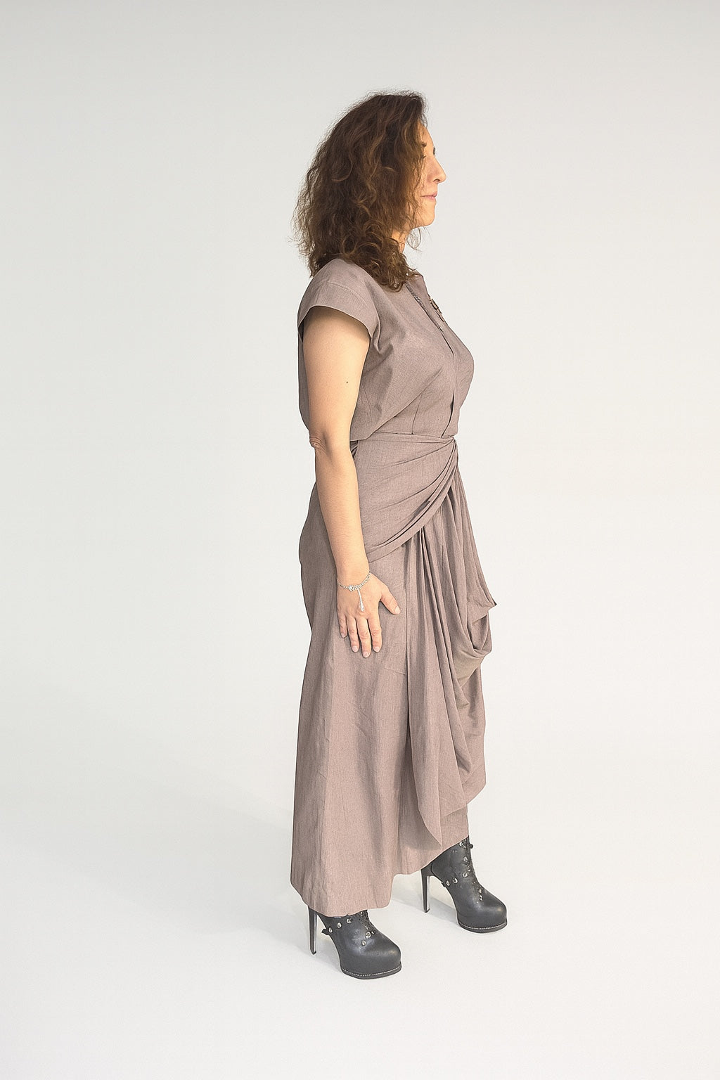 Crater Matter Set : Close-up side view of a woman wearing a taupe draped Top with pleated detailing at the waist and cascading fabric drape, styled with black high-heel ankle boots and minimal silver jewelry, elegant taupe Gray Beige Topwith cascading side drape | Women's Top | Pret Clothes | Asymmetrical  Top | nEo Clothes 