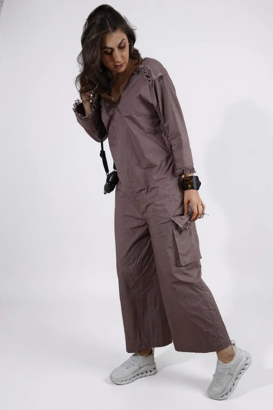 Dust Moon Jumpsuit :Woman wearing a beige wide-leg jumpsuit with lace trim on neckline, hand cuffs, and pocket, paired with sneakers. stylish lace detail jumpsuit with long sleeves and relaxed fit - near Earth object | Women Jumpsuit | Pret Clothes | nEo Clothes | Asymmetrical 