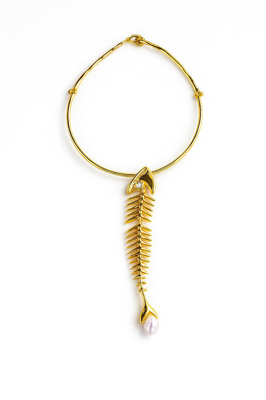 Gold necklace featuring a sculptural fish-bone pendant and pearl drop on a white background.