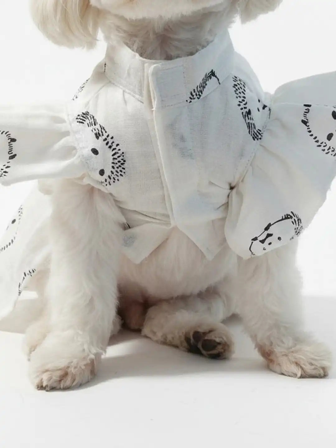 Small dog wearing a white outfit with black patterns 