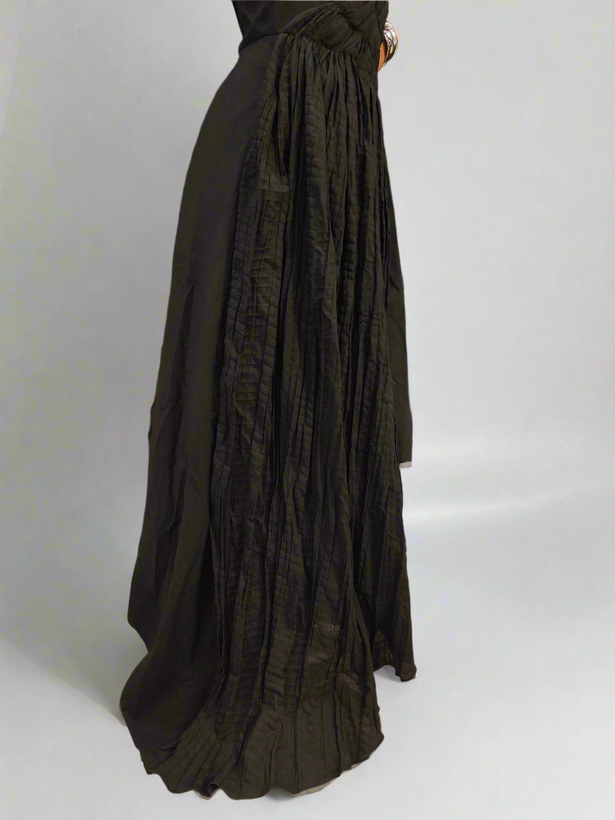 close-up of the lower half of a black asymmetrical Jumpsuit with features a flowing layered hemline with prominent vertical pleated detailing cascading down the fabric The material appears lightweight yet structured, emphasizing movement and craftsmanship, | Women's Jumpsuit | Pret Clothes | Asymmetrical Jumpsuit  | nEo Clothes