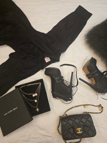 Near Earth Object | Black clothing, shoes, handbag, and jewelry on a light surface
