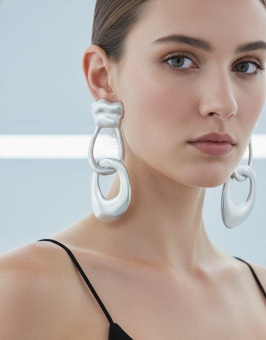 Model wearing silver sculptural loop earrings in a futuristic corridor – contemporary statement jewellery by Near Earth Object.