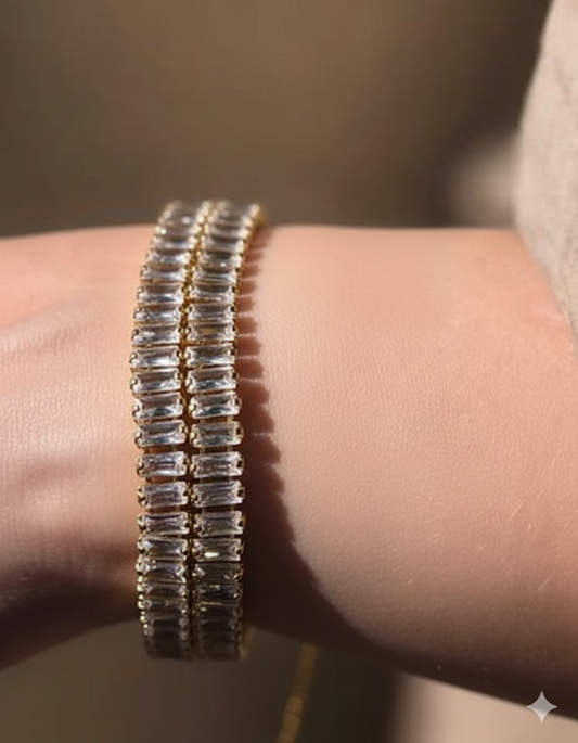 Gold baguette-cut crystal bracelets worn on wrist in warm natural lighting – layered luxury jewellery styling by Near Earth Object.