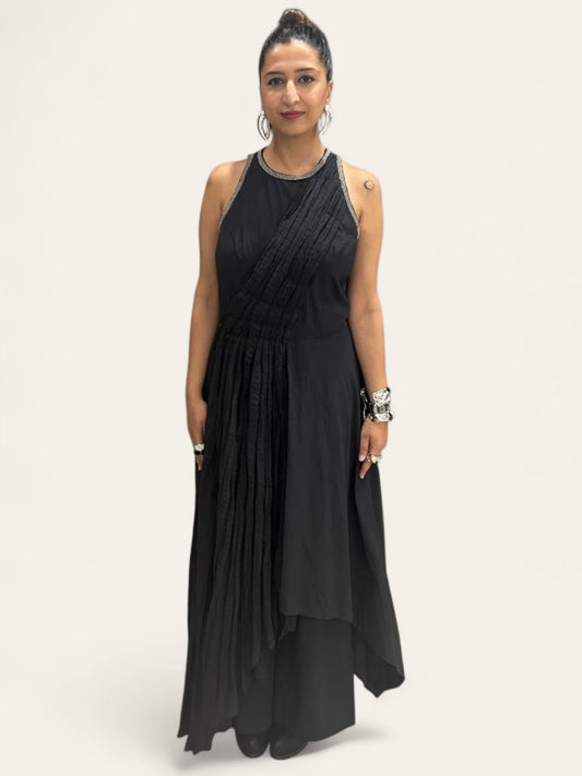 Moon Crescent Jumpsuit : Women wearing a modern black asymmetrical Jumpsuit with pleated detailing, a sleeveless design with metallic edging at the neckline. Accessorizes with bold silver jewelry including hand cuff, stacked rings, and hoop earrings, The overall style is a fusion of contemporary and ethnic fashion, giving off a confident, Trendy sleeveless Jumpsuit outfit for women with ethnic silver jewelry - near Earth object | Women's Jumpsuit | Pret Clothes | Asymmetrical Jumpsuit | nEo clothes