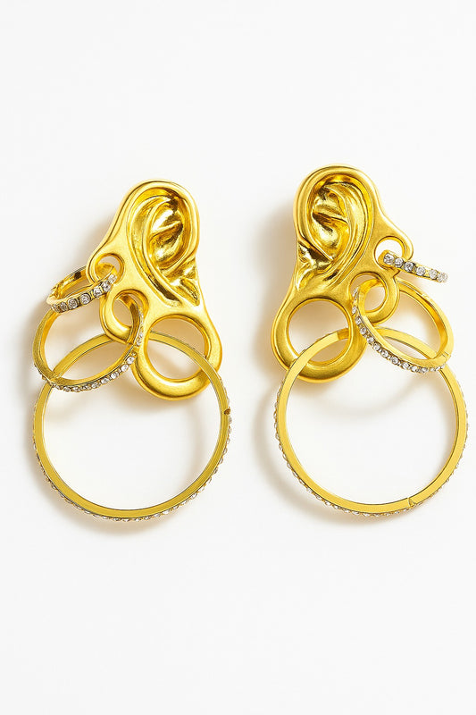 Gold sculptural ear-shaped earrings with layered crystal hoops