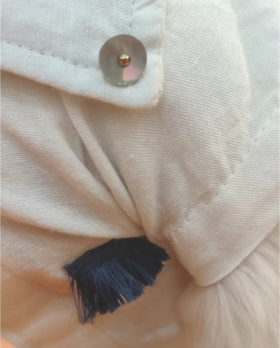 Close-up of a beige fabric with a button and black thread detail