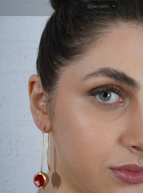Close-up of a woman wearing a Minimalist hook gold earring with a red gemstone | Statement Earrings | neo jewelry 