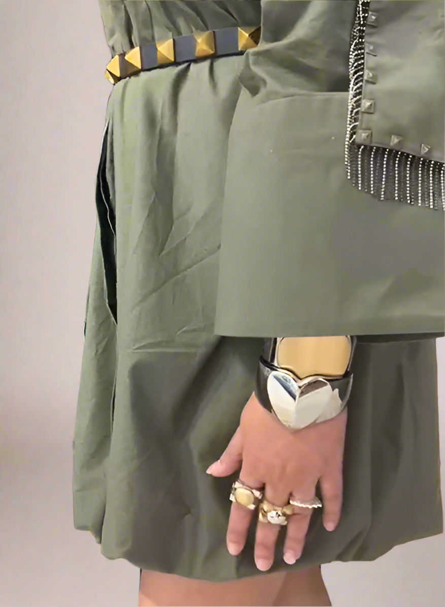 Detail of olive green shirt dress with pyramid studded belt, metallic sleeve accents, and statement jewelry including silver cuff bracelet and rings. | Women's Dress | Pret Clothes | Asymmetrical Dress | nEo Clothes
