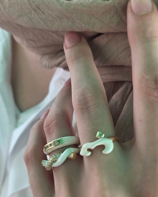 Model wearing white enamel and gold sculptural rings stacked on fingers, showcasing bold modern jewellery styling by Near Earth Object.