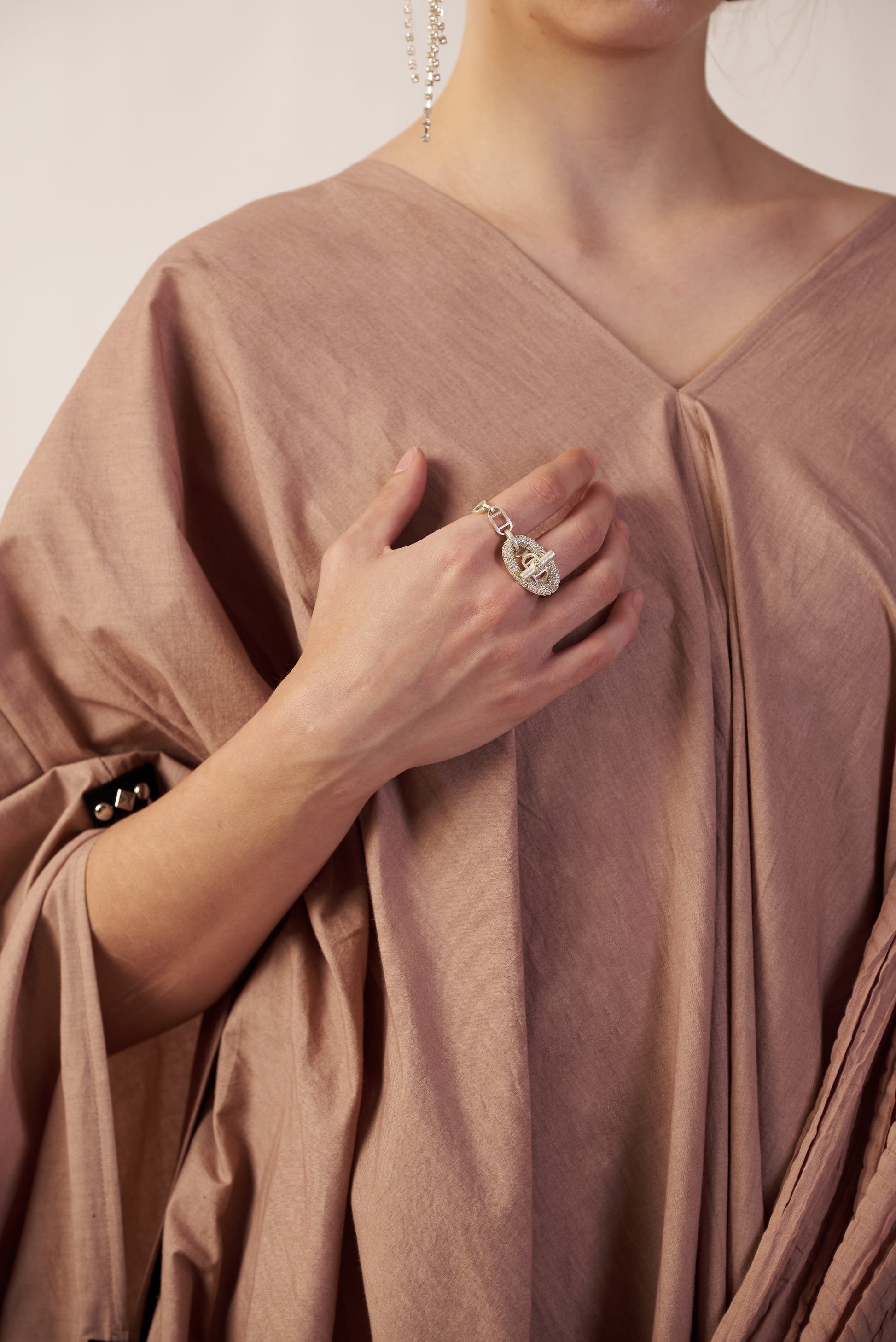 Person wearing a beige dress with a close-up of a hand holding a ring. | Women Dresses | Pret Clothes | nEo Clothes.
