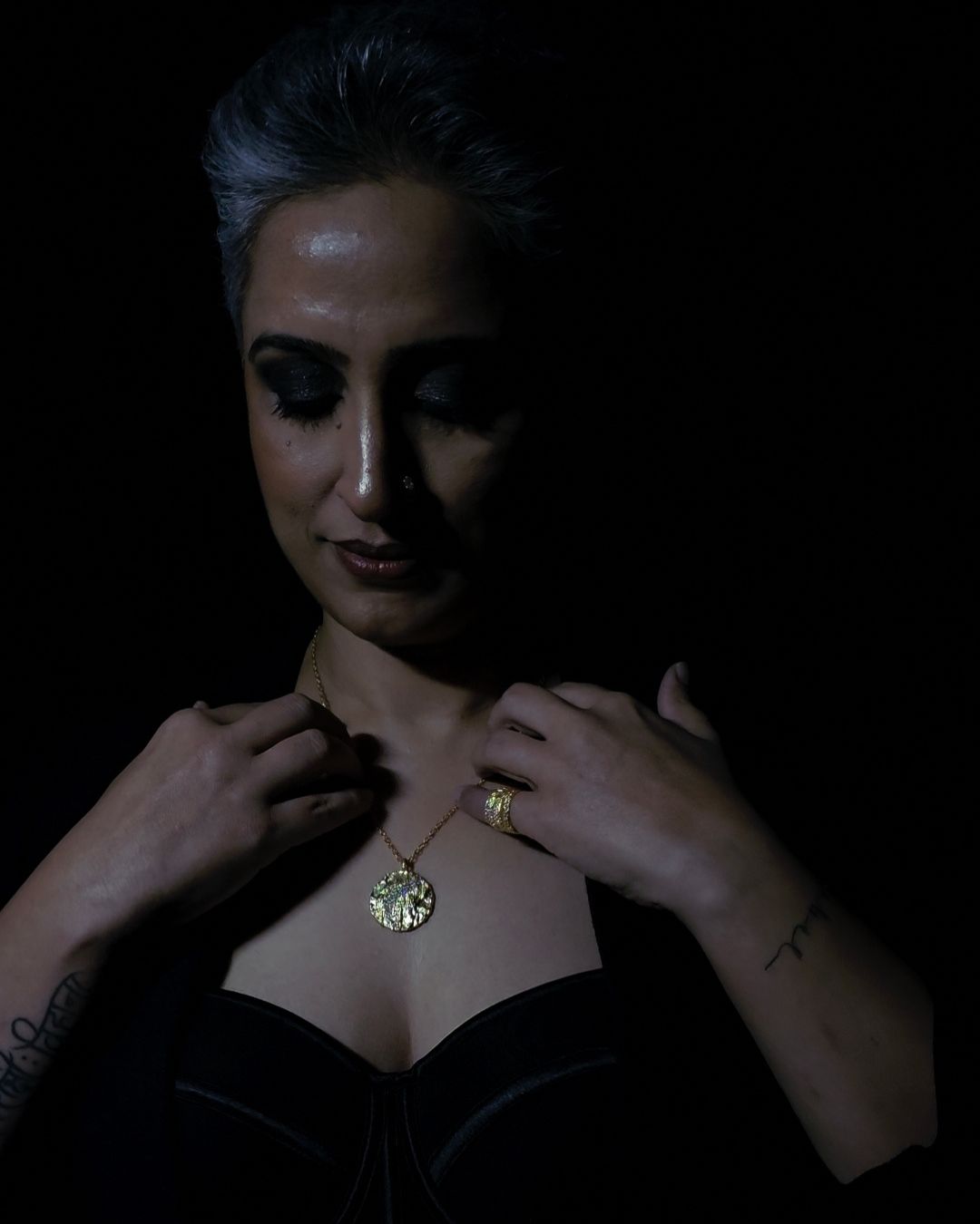 Near Earth Object | Woman wearing a gold necklace against a dark background