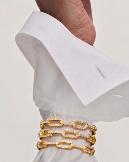 Near Earth Object | Gold bracelet on a white shirt cuff against a light background