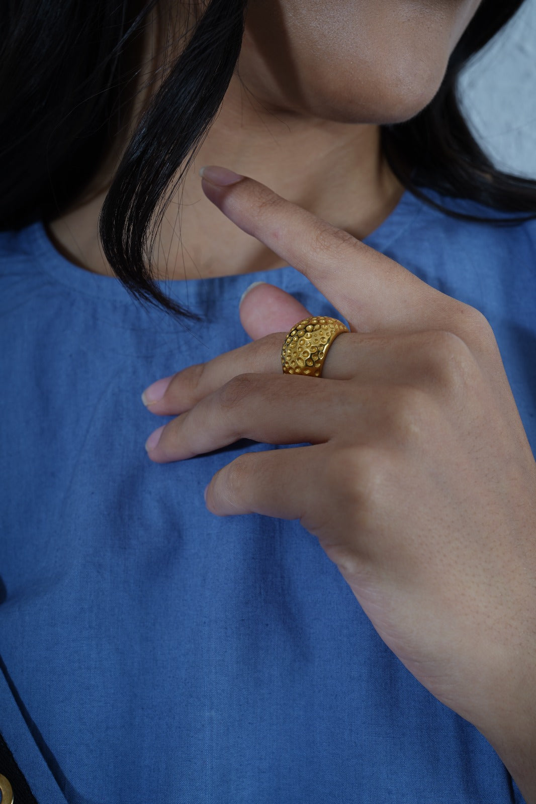 Close-up of a person wearing a gold ring on a blue shirt.| Statement Ring | Asymmetrical Ring  | neo jewelry 
