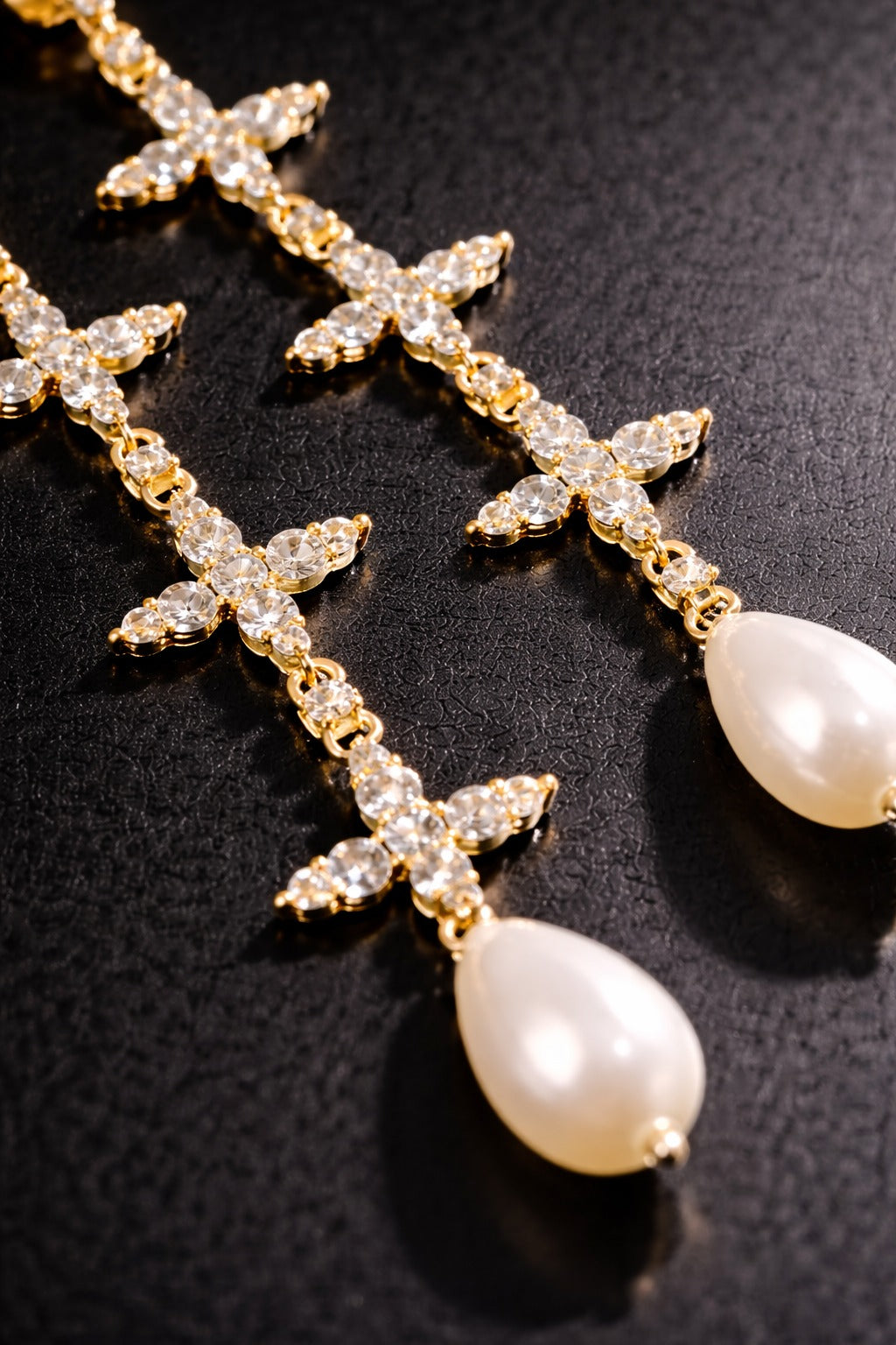 Near Earth Object | Gold cross-shaped earrings with pearl drops on a black background