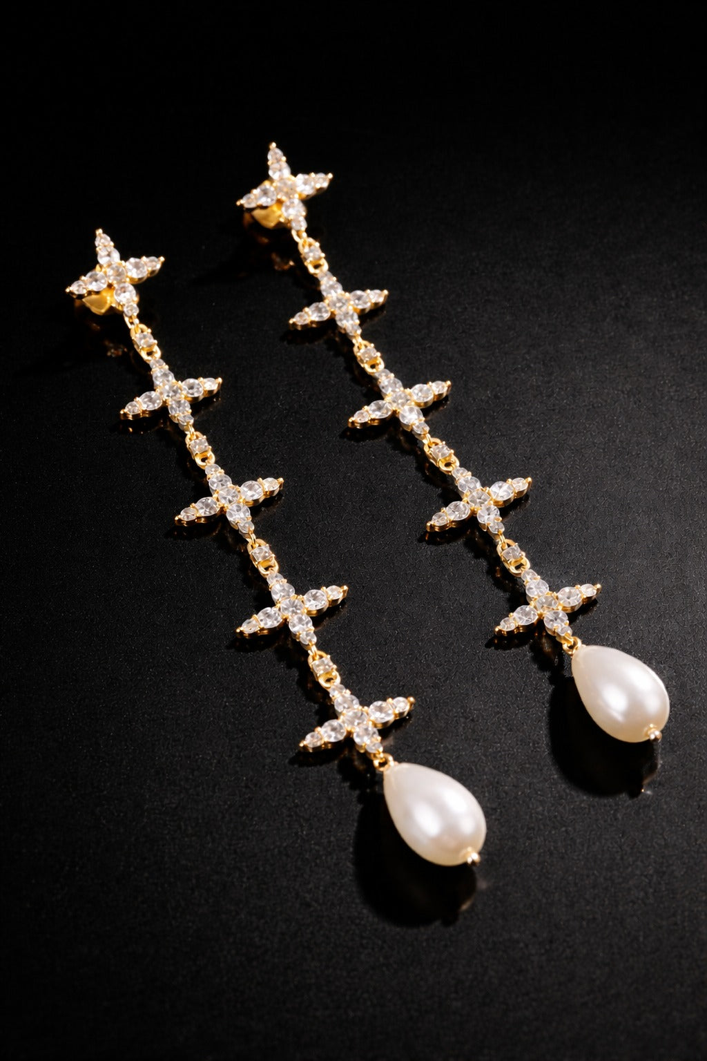 Near Earth Object | Pair of gold earrings with pearl drops on a black background