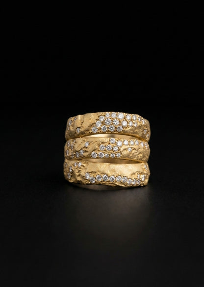 Near Earth Object | Three gold rings with diamond accents stacked on a black background