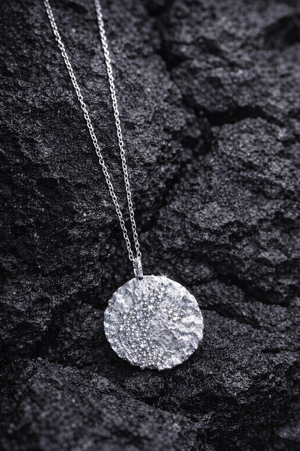 Near Earth Object | Silver necklace with a round pendant on a dark textured surface