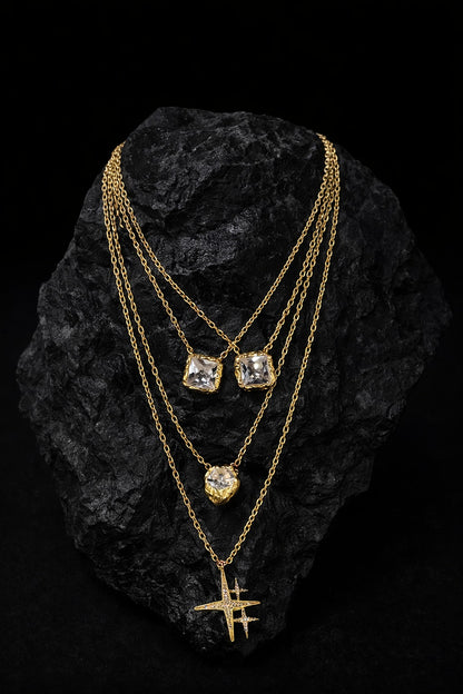 Near Earth Object | Gold necklaces with gemstones on a black textured surface