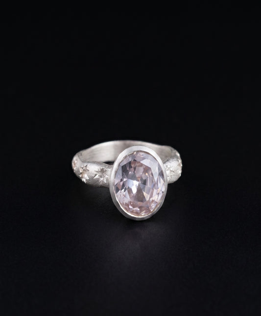 Near Earth Object | Silver ring with a pink gemstone on a black background