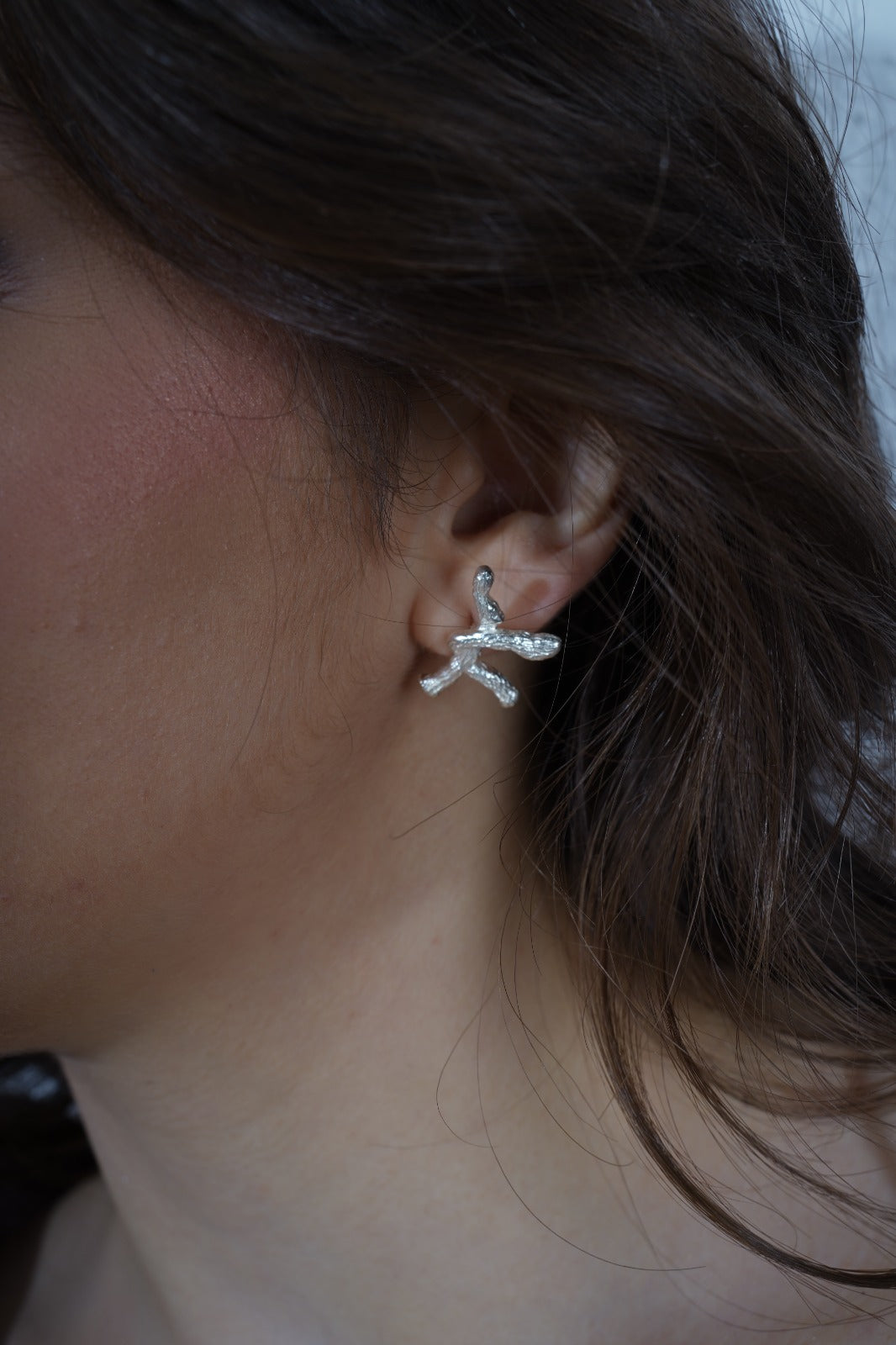 Close-up of an ear wearing a star-shaped silver earring  | Statement Earrings | neo jewelry 