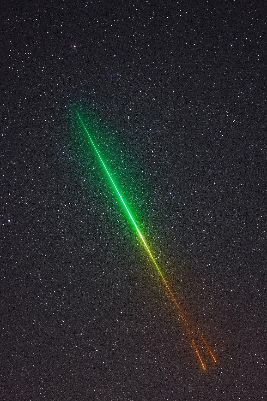 Two laser beams, one green and one orange, crossing each other against a starry night sky. | Statement Earring | neo jewelry