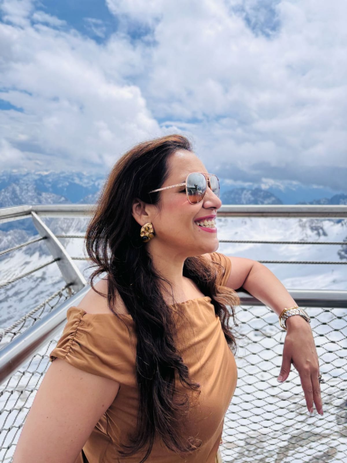 Woman Wearing a Gold Gemstones with sunglasses and a tan top standing on a balcony with mountains | Statement Earrings | neo jewelry 