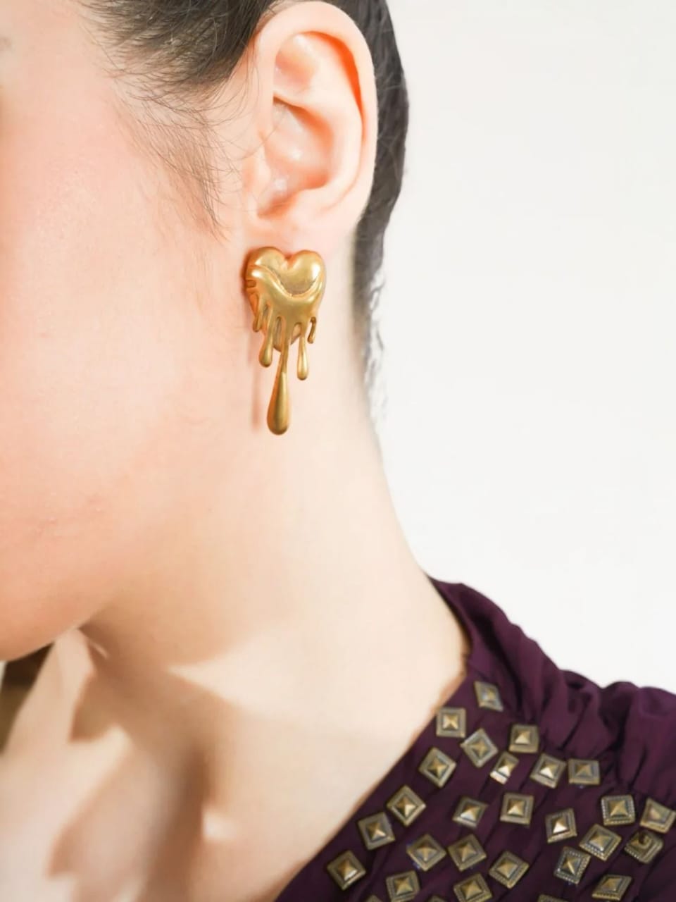 Gold heart-shaped earring worn by a person | Statement Earrings | neo jewelry 