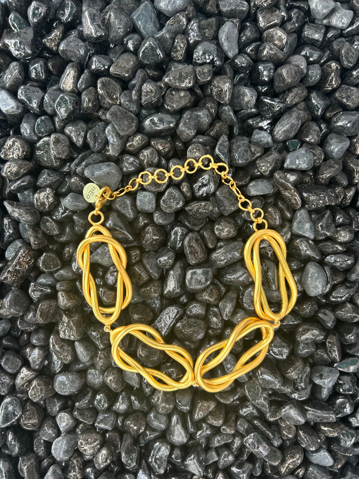 Gold Necklace on a bed of dark pebbles | Statement Necklace & Chokers | neo jewelry
