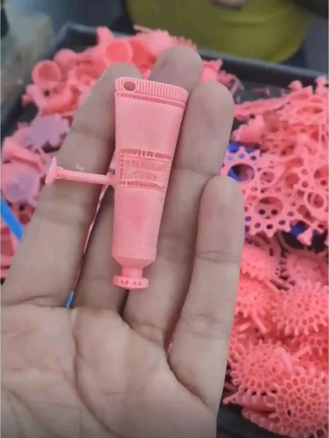 Hand holding a small pink tube with a colorful background