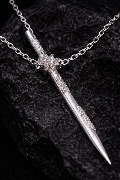 Near Earth Object | Silver dagger-shaped necklace with chain on a dark textured background